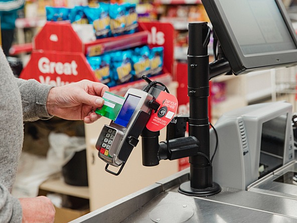 person paying at a supermarket till using contactless card